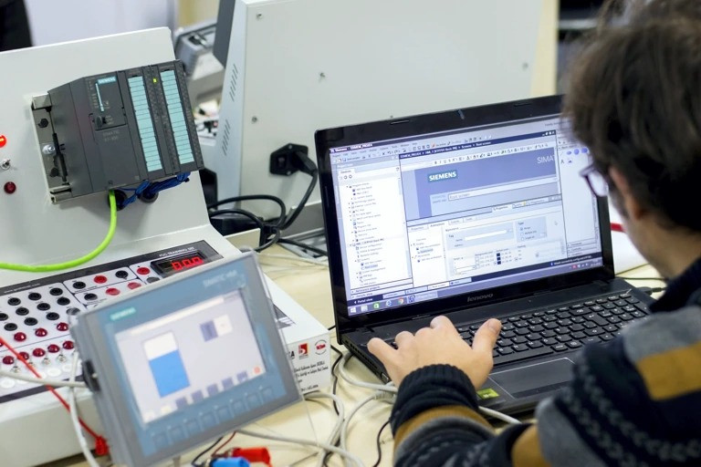Technik analizujący dane z czujników na panelu sterowania linii produkcyjnej.